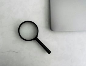 Magnifying glass sits near a laptop on a table.